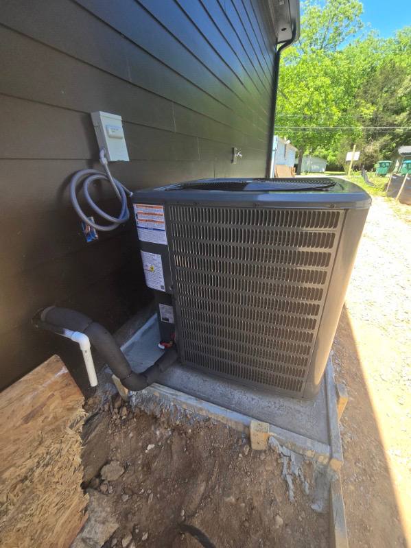 Outdoor HVAC equipment beside a dark-sided home
