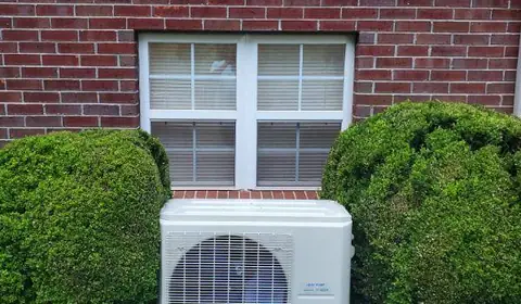 Outdoor mini-split system beside a brick home