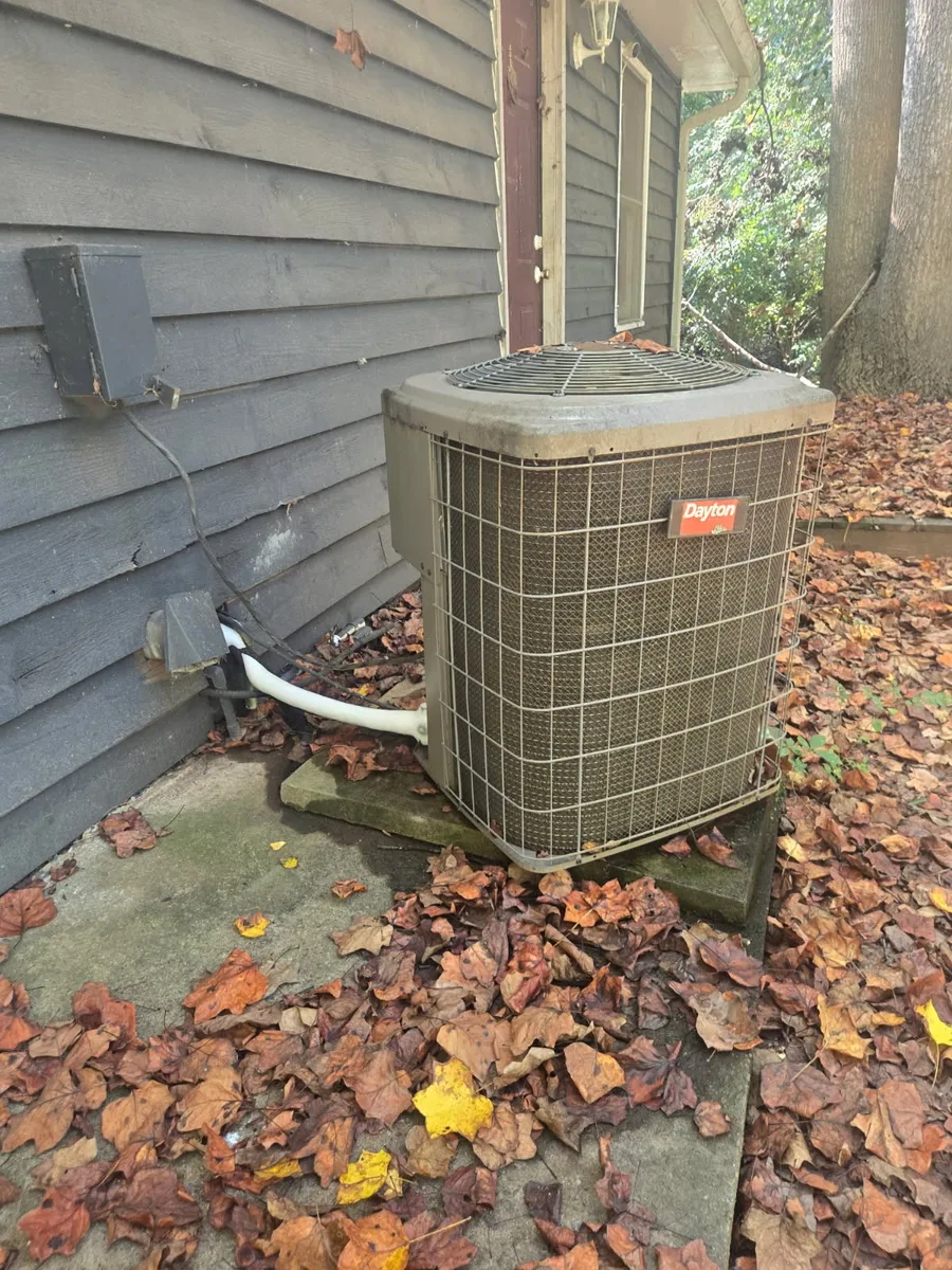 Weathered Dayton outdoor condenser on a concrete pad beside a home