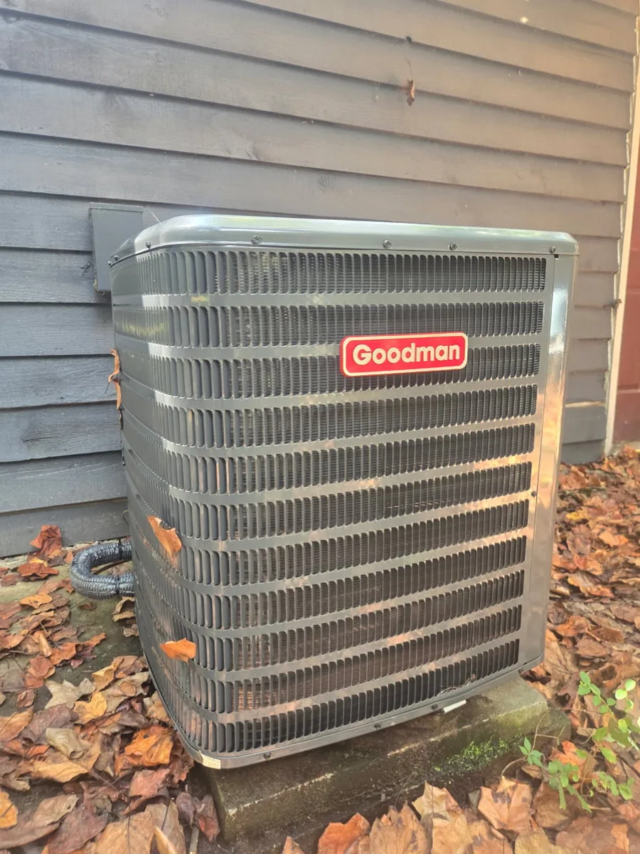 Goodman outdoor condenser on a concrete pad beside a home