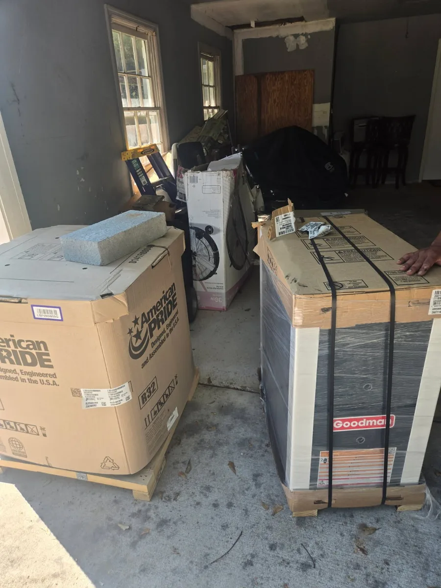 New R-32 air handler and a crated Goodman condenser staged in a garage before installation